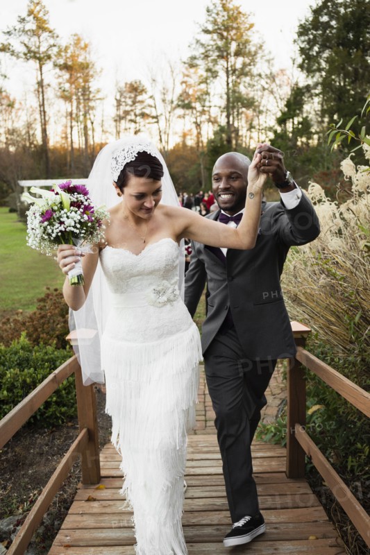 Newlywed couple walking on wooden footbridge