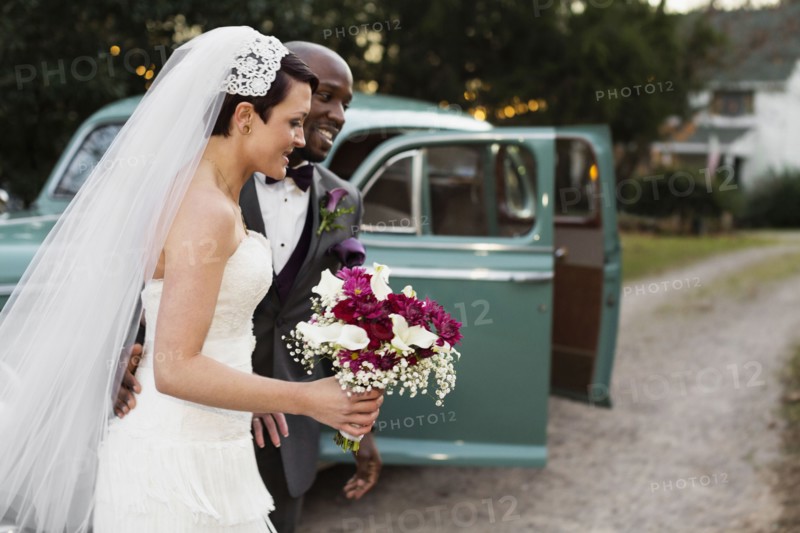 Newlywed couple outside vintage car