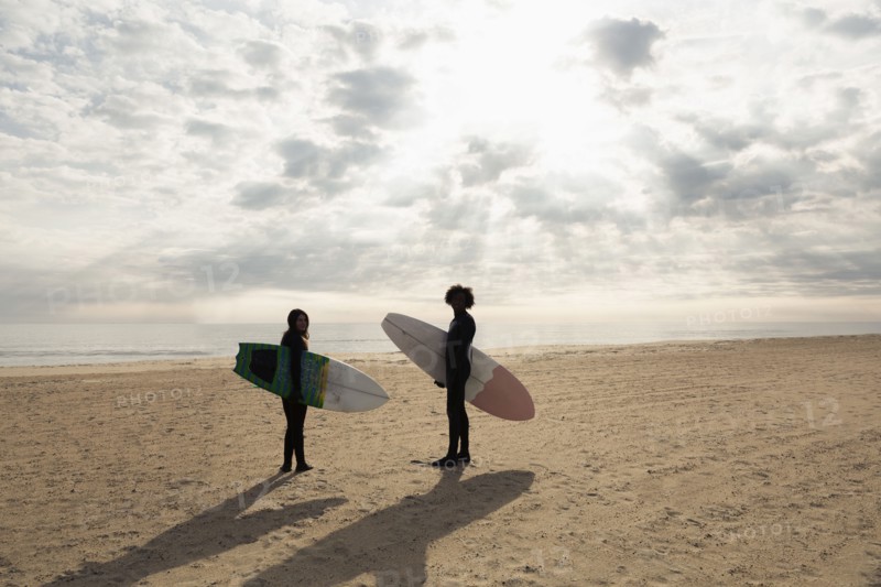 Surfers carrying boards on beach