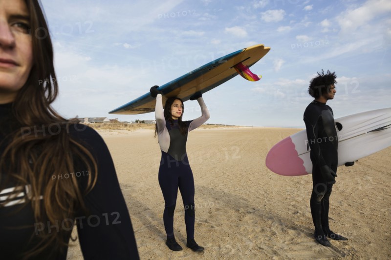 Surfers carrying boards on beach