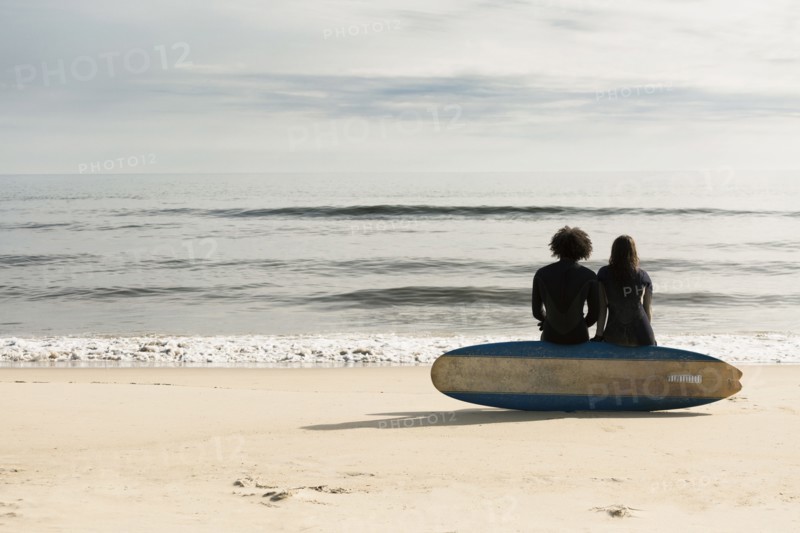 Surfers sitting on board on beach