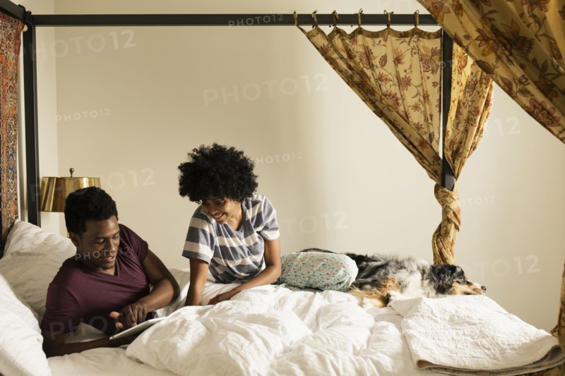 Couple and dog relaxing on bed