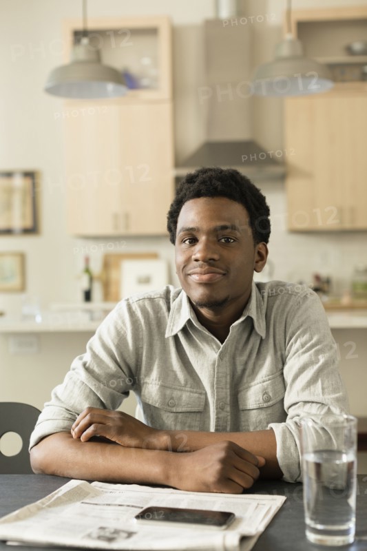 Black man reading newspaper at breakfast table