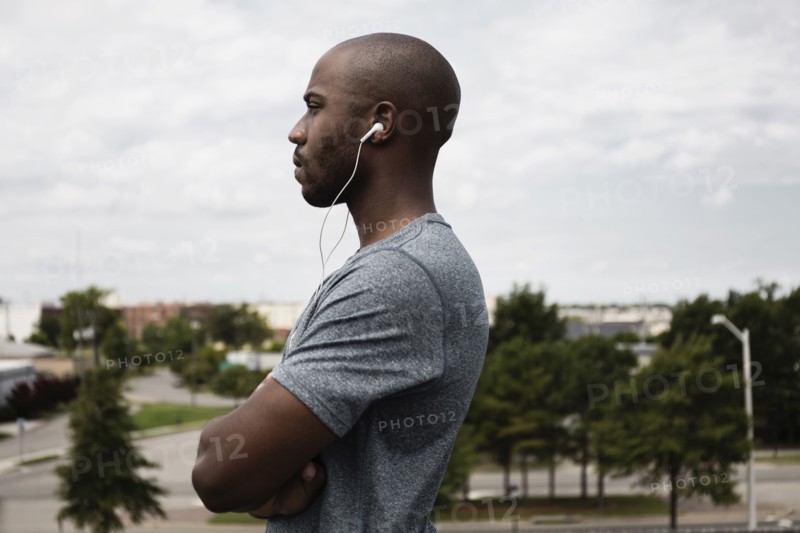 Black runner listening to earbuds in urban park