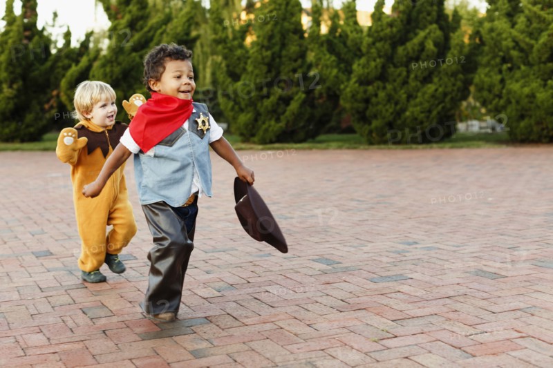 Boys playing in costumes on sidewalk