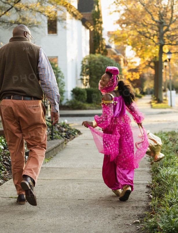 African American girl trick-or-treating with father on Halloween
