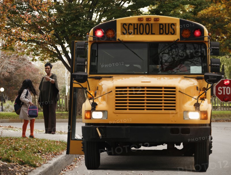 African American woman waiting with daughter for school bus