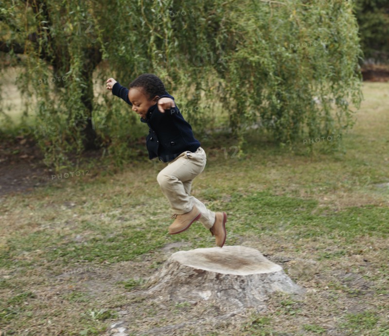 African American boy playing on stump in park