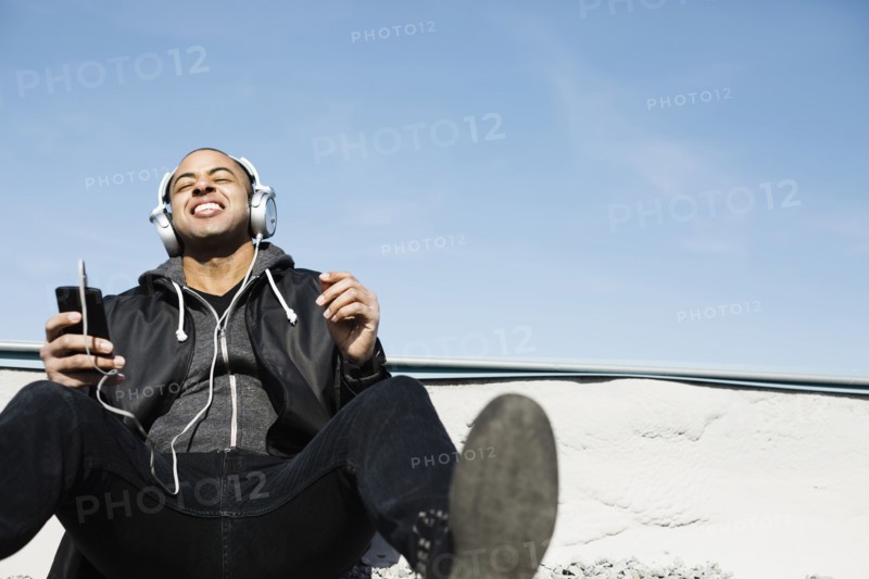 Mixed race man listening to headphones on beach