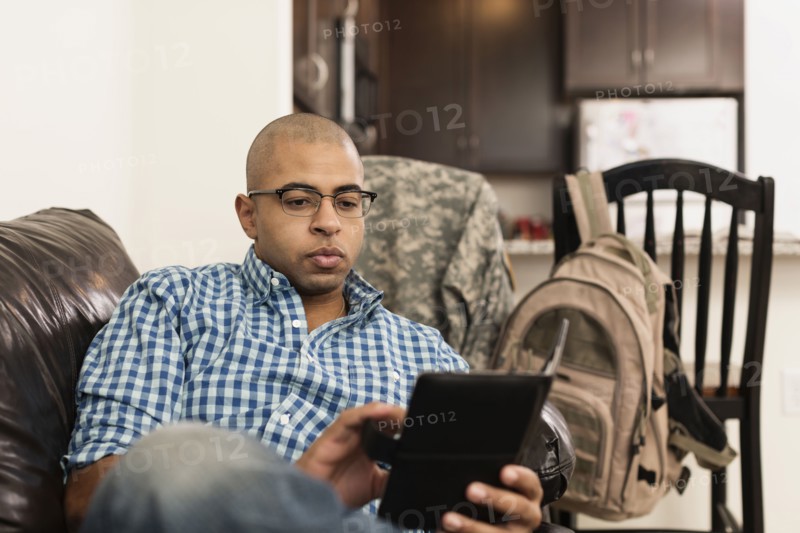 Mixed race man using digital tablet on sofa in living room