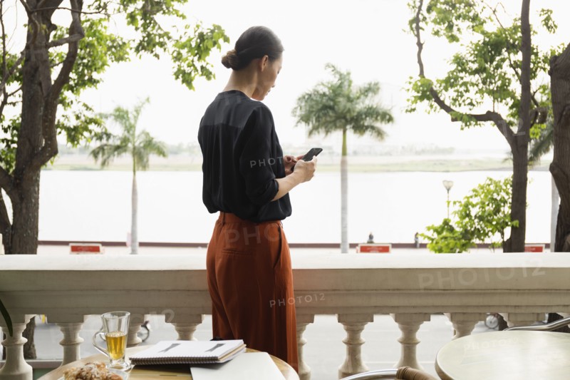 Asian businesswoman using cell phone on balcony