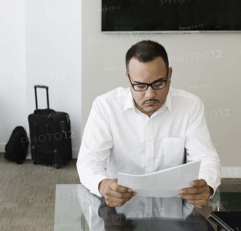 Hispanic businessman reading paperwork in office