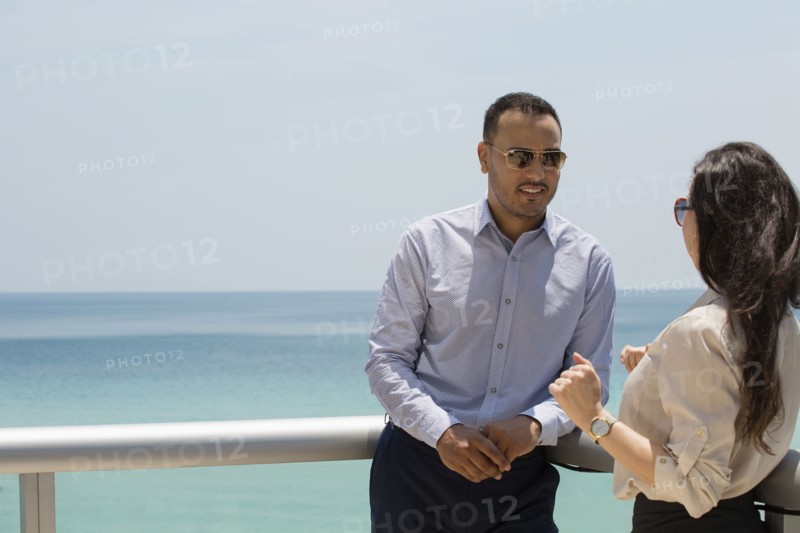 Business people talking on balcony over ocean