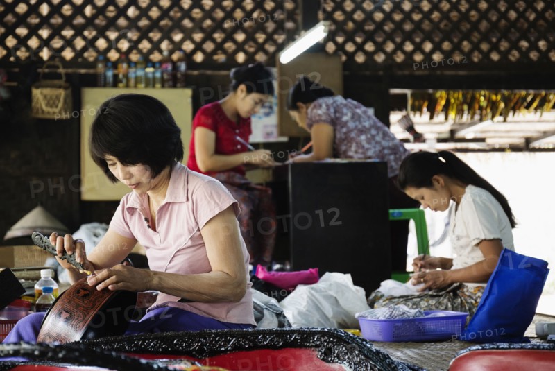 Asian artisans carving traditional designs in workshop