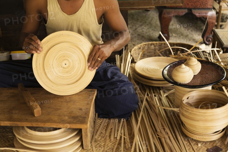 Asian artisan weaving traditional baskets in workshop