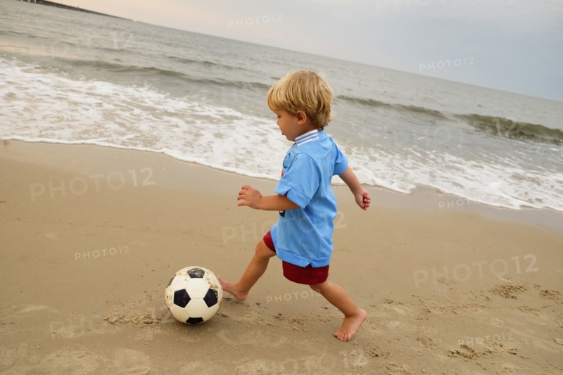 Caucasian boy playing with soccer ball on beach