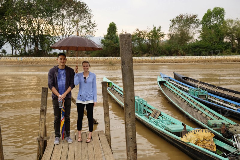Couple standing under umbrella on wooden dock