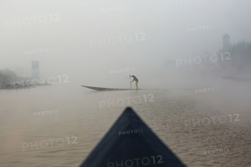 Asian woman rowing canoe on rural lake