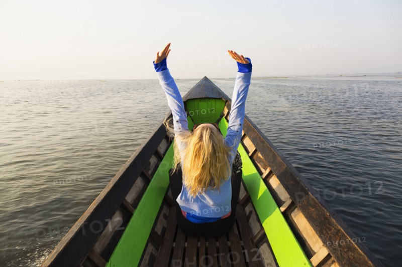 Caucasian woman cheering in canoe on lake