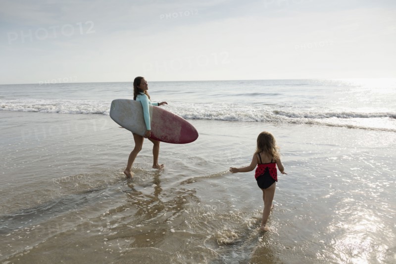 Mother and daughter playing in waves on beach