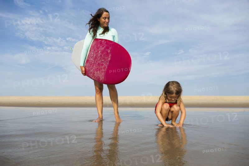Mother and daughter playing in waves on beach