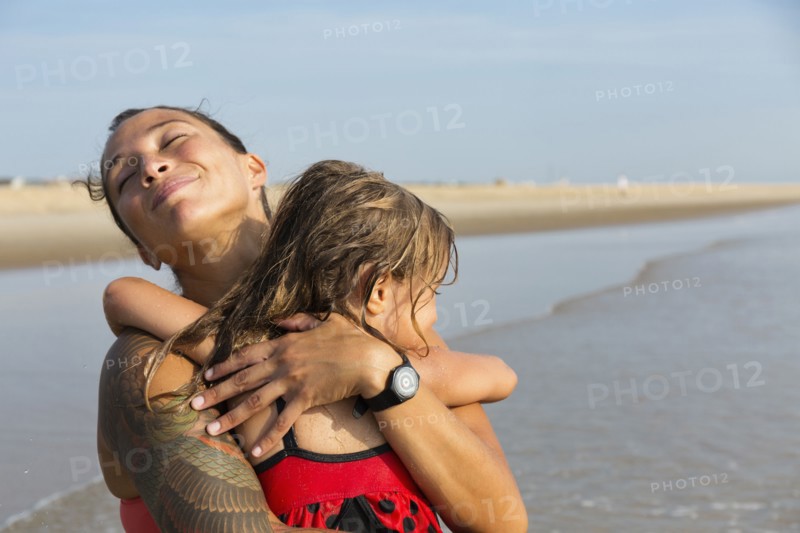 Mother and daughter hugging on beach