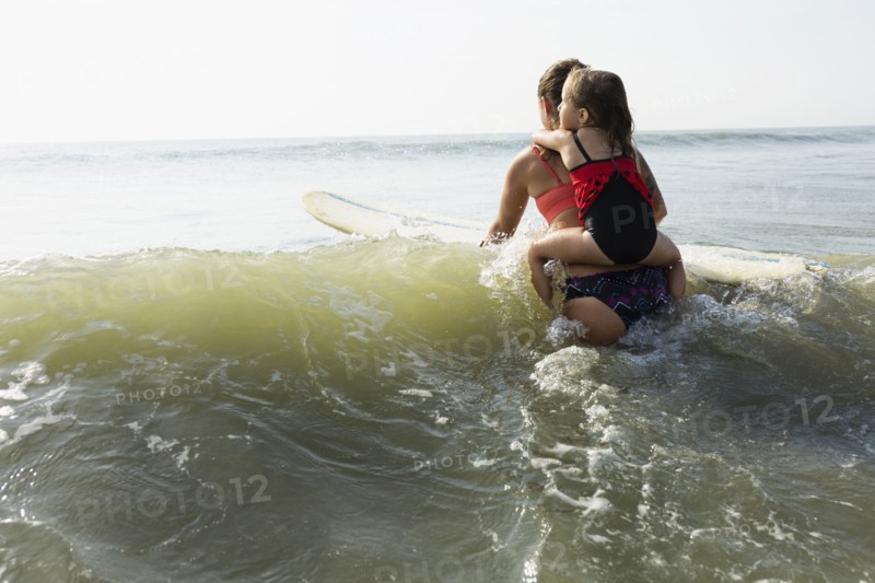Mother and daughter surfing in waves