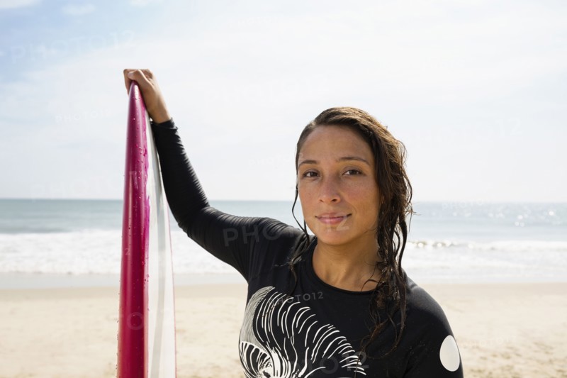 Hispanic surfer holding surfboard on beach