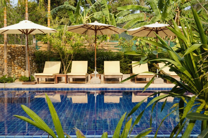 Empty lawn chairs by swimming pool