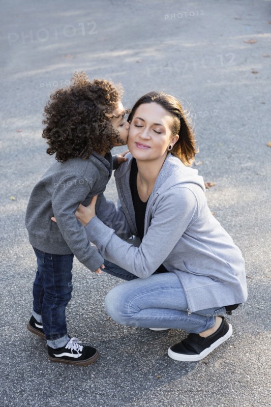 Boy kissing cheek of mother outdoors
