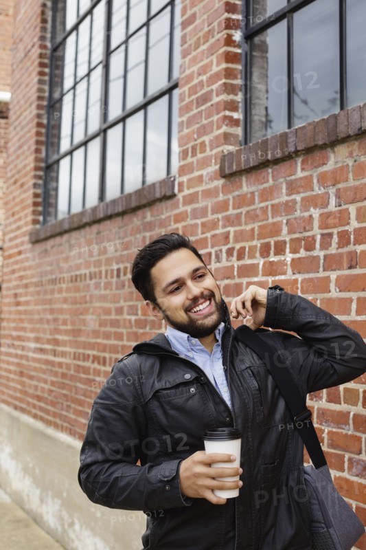 Hispanic man carrying bag and coffee cup in city
