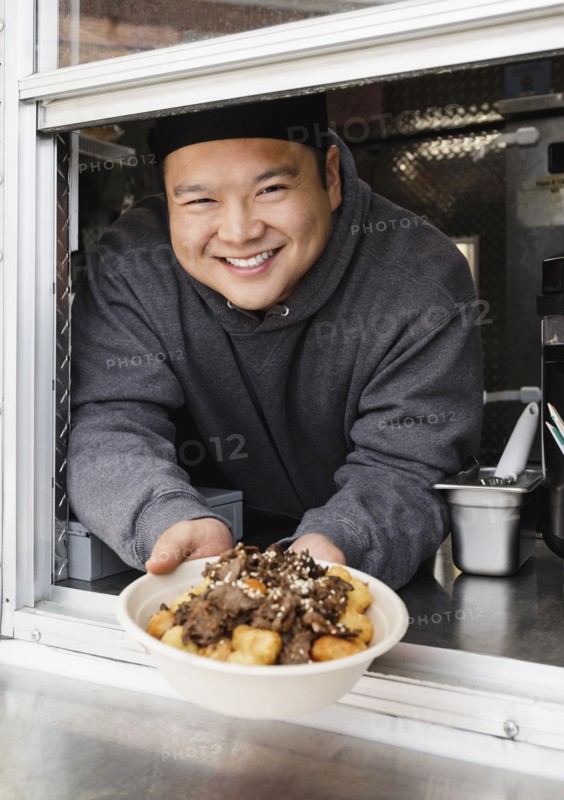 Proud Asian man showing bowl of food at food truck