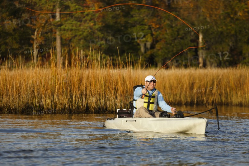 Caucasian man fly fishing in kayak on river