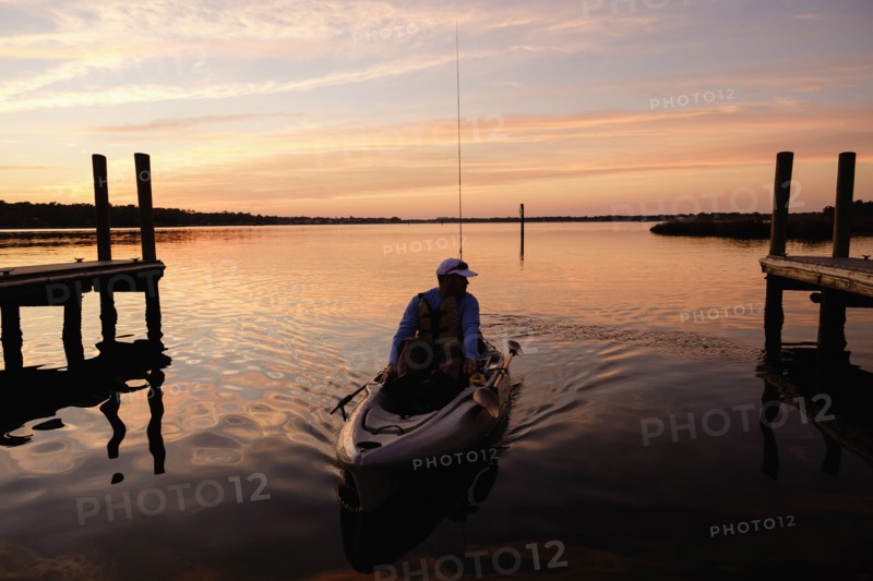 Caucasian man on kayak near dock at sunset