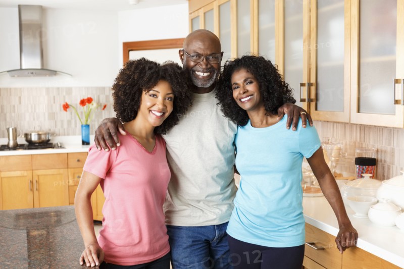 Black family hugging in kitchen