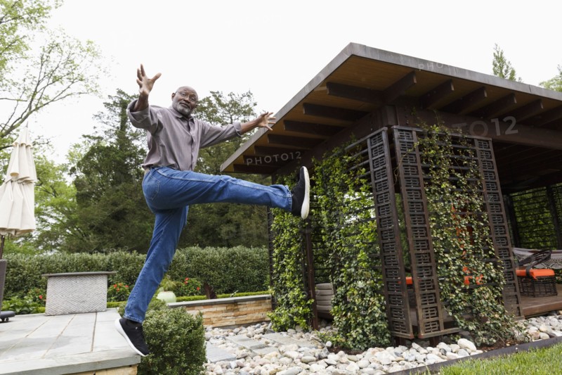 Black man jumping mid-air from bench in garden