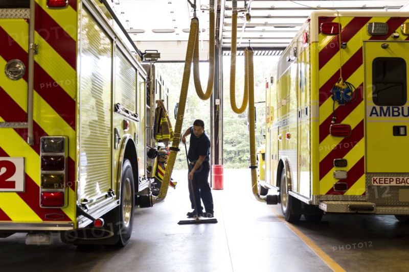 Chinese fireman sweeping floor near fire trucks