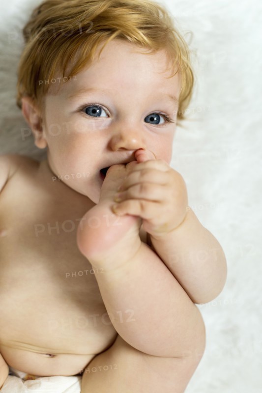 Caucasian baby boy biting foot