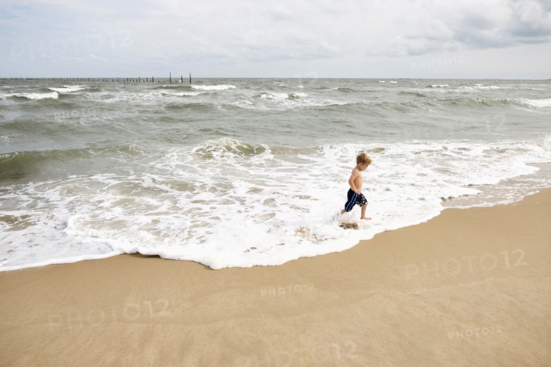 Caucasian boy running in waves at beach