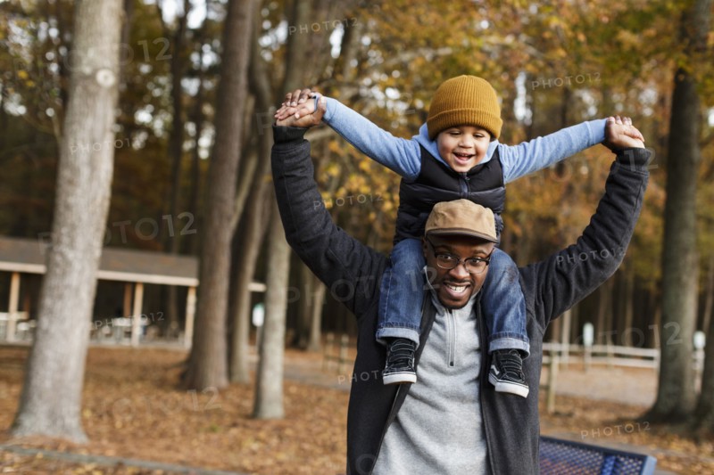 Father carrying son on  shoulders in park