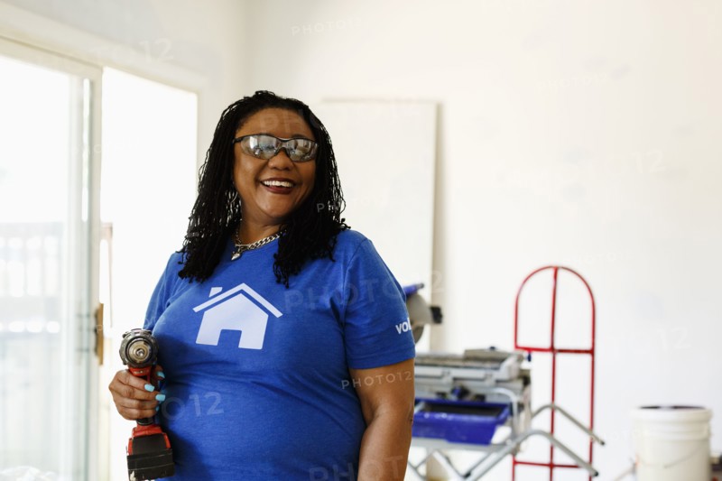 Black volunteer woman holding drill