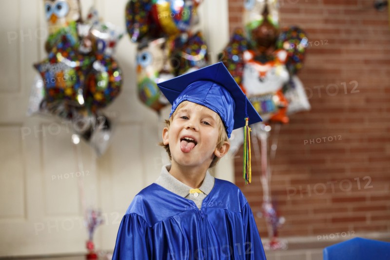 Caucasian boy wearing graduation robe sticking tongue out