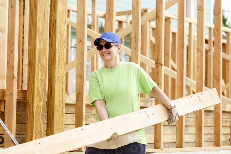 Caucasian woman carrying lumber at construction site