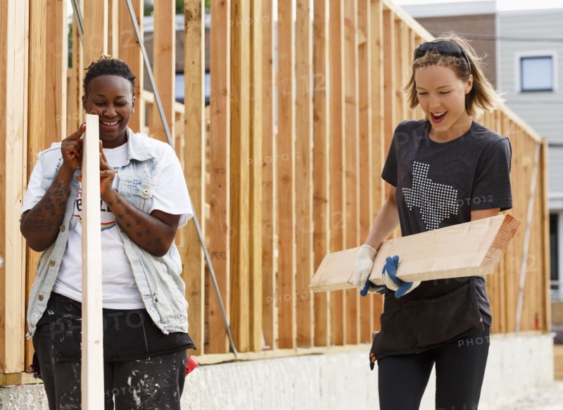 Volunteers carrying lumber at a construction site