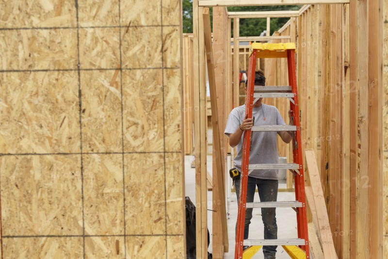 Caucasian woman carrying ladder at construction site