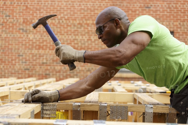 Black man hammering nail at construction site