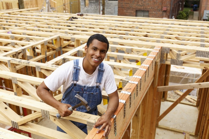 Portrait of mixed race man hammering nail at construction site