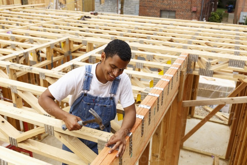Mixed race man hammering nail at construction site
