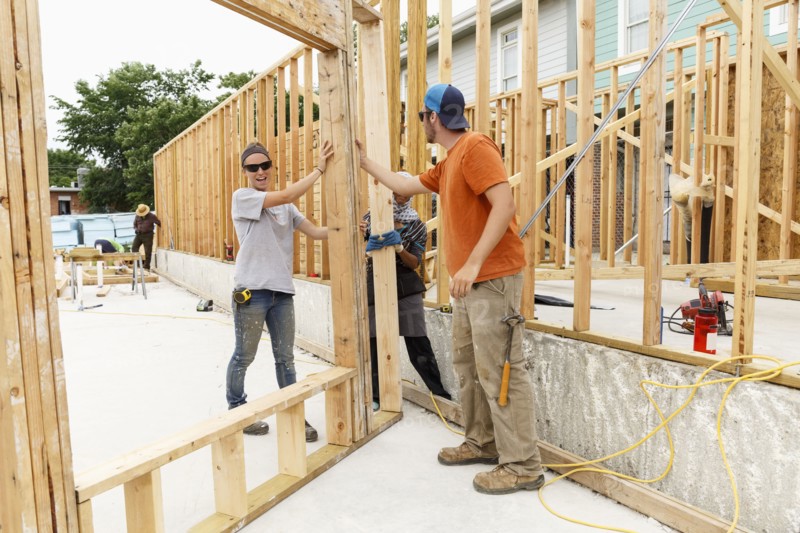 Volunteers holding framed wall at construction site