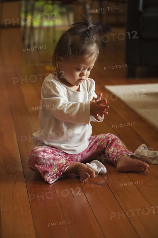 Mixed race baby with Down syndrome playing on floor